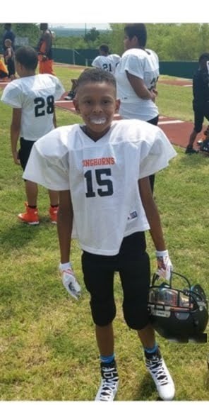A young John Meredith III in his No. 15 youth Longhorns practice jersey, holding his helmet
