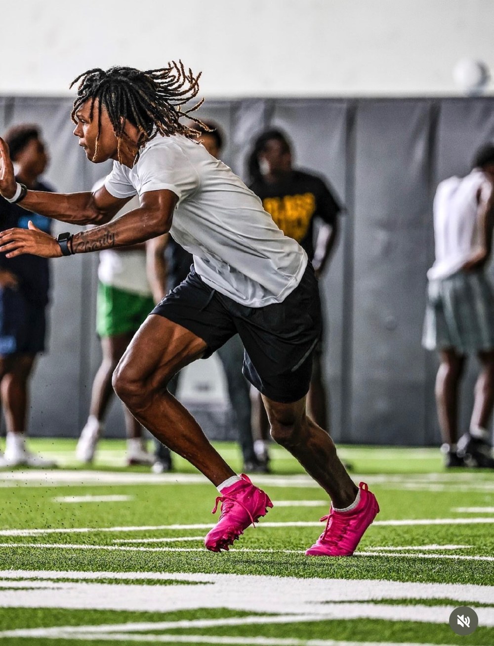 John Meredith III sprinting through a speed drill in pink cleats