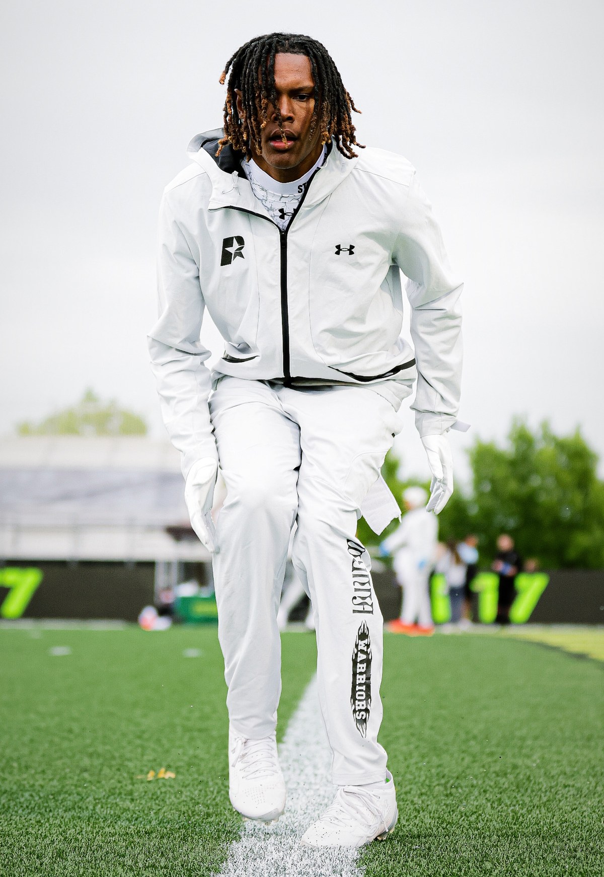 John Meredith III in an all-white warmup walking the sideline before a game