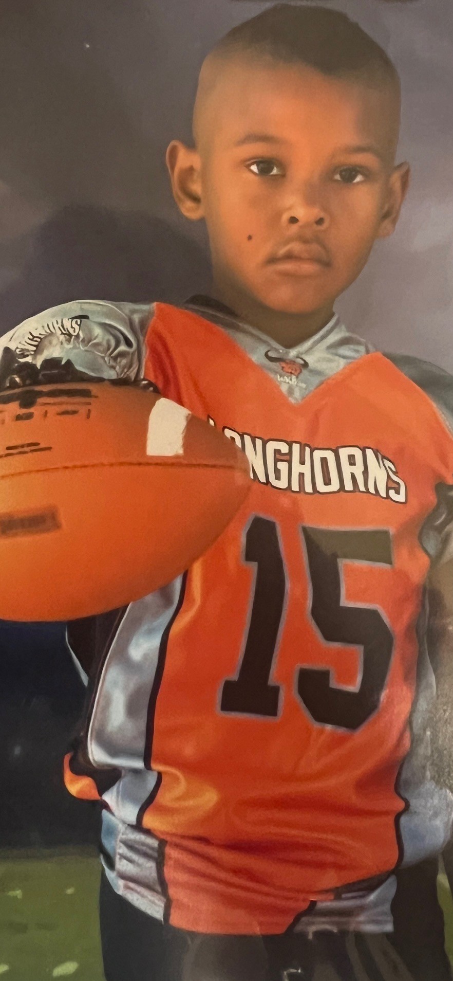 Young John Meredith III in youth football uniform No. 15